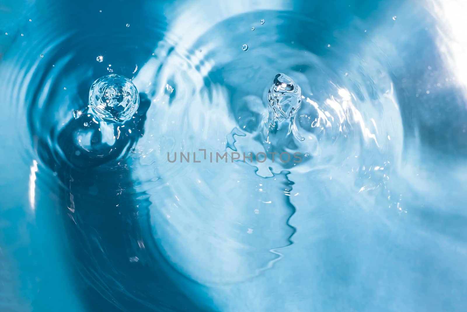 Water splash close-up. Drop of water. Blue water drop. Falling blue water surface with splash and air bubbles