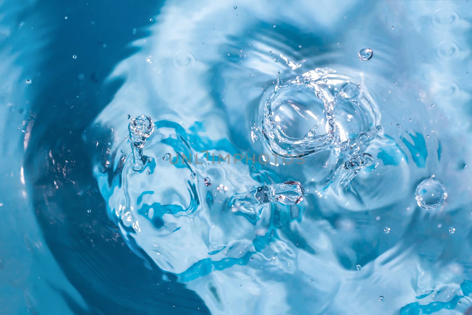 Water splash close-up. Drop of water. Blue water drop. Falling blue water surface with splash and air bubbles