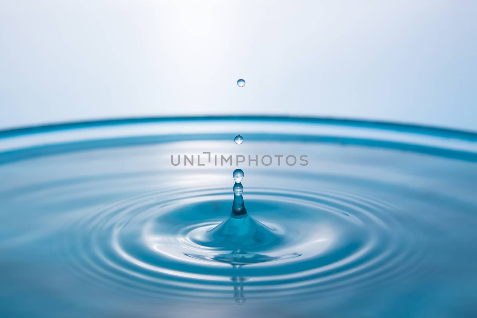 Water splash close-up. Drop of water. Blue water drop. Falling blue water surface with splash and air bubbles