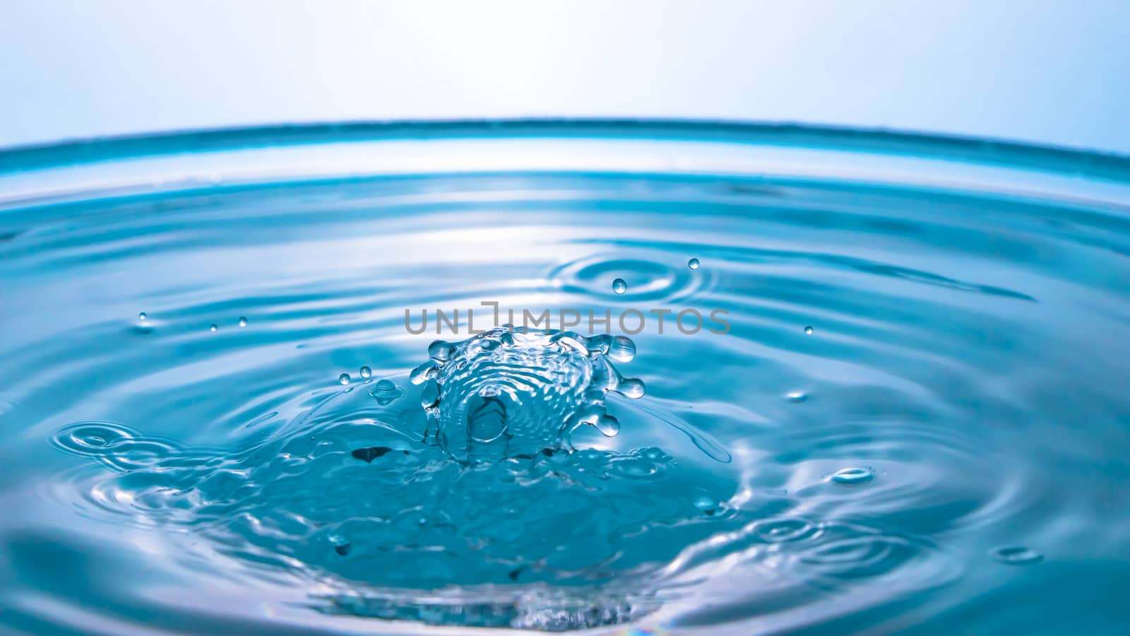 Water splash close-up. Drop of water. Blue water drop. Falling blue water surface with splash and air bubbles