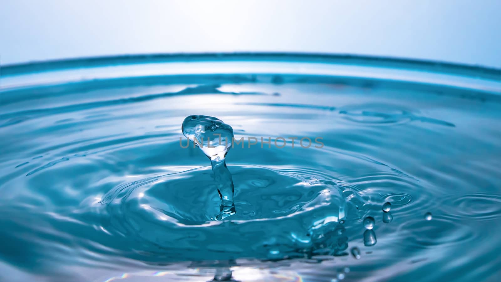 Water splash close-up. Drop of water. Blue water drop. Falling blue water surface with splash and air bubbles