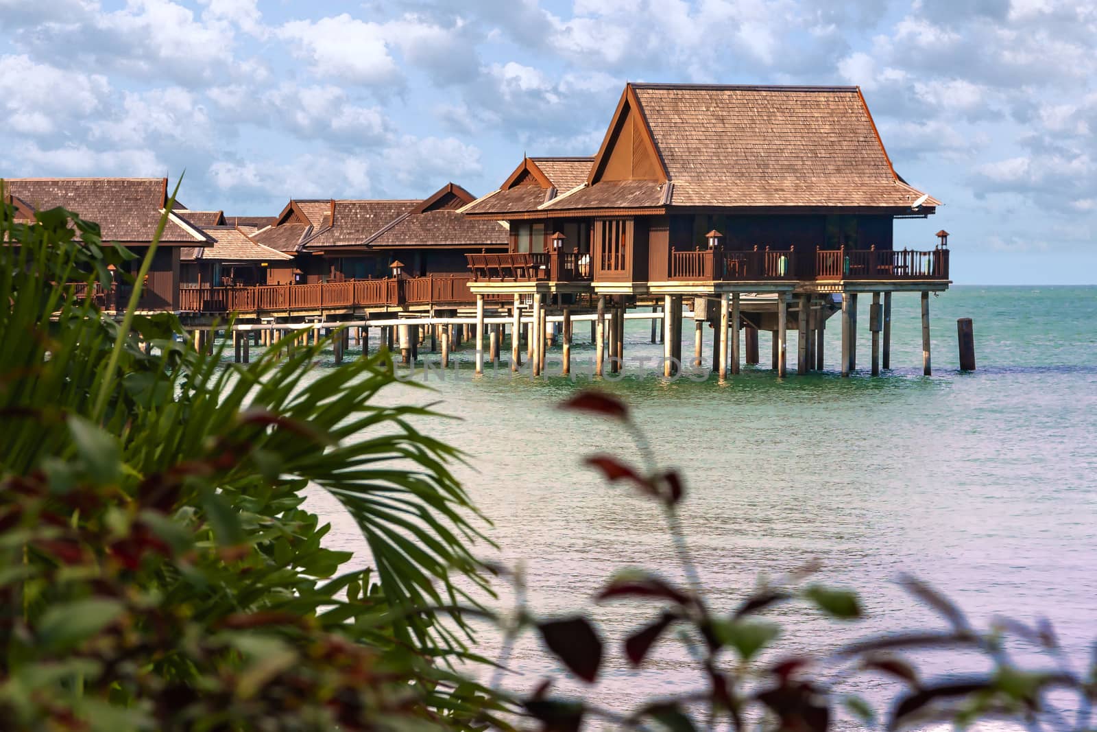 Wooden cottages, bungalows on clear blue water waiting for tourists in tropical oceans 
