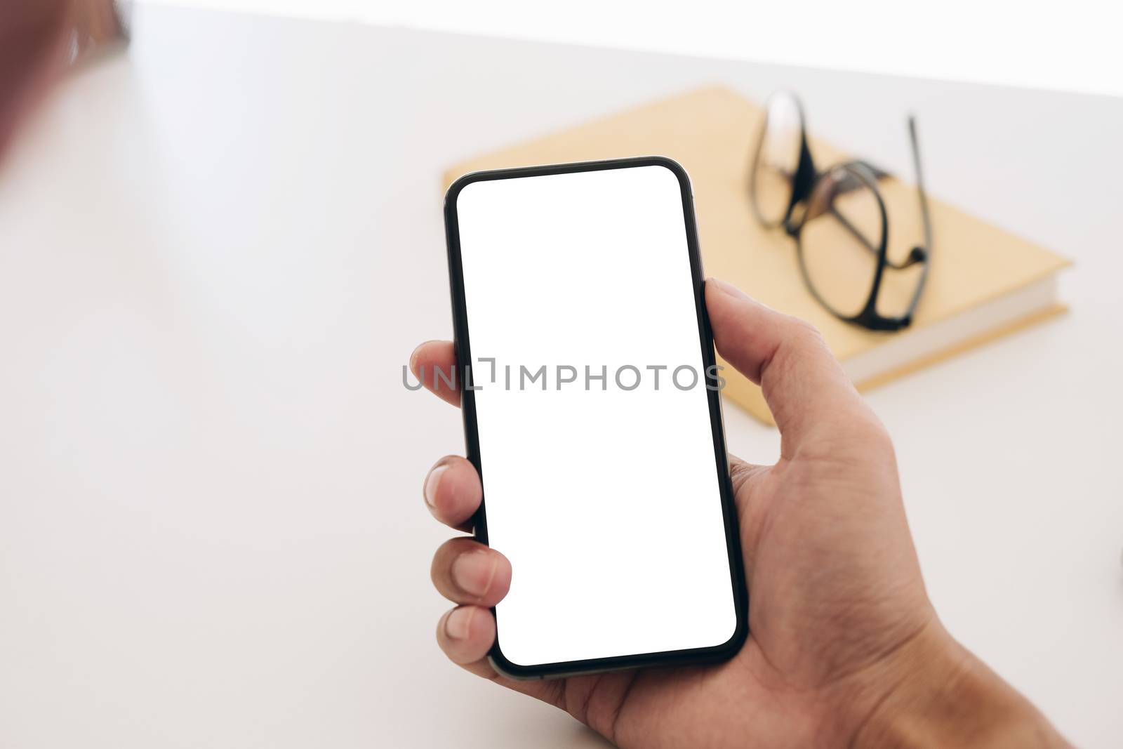 Top view man sitting and holding blank screen mock up mobile pho by wichayada