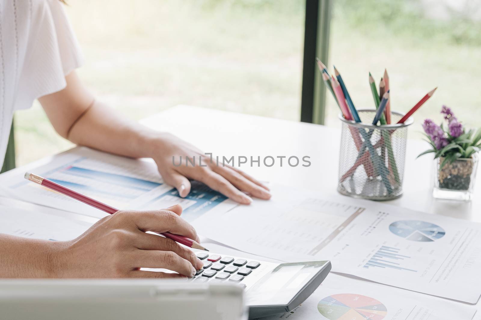 Business woman using calculator and laptop for do math finance o by wichayada