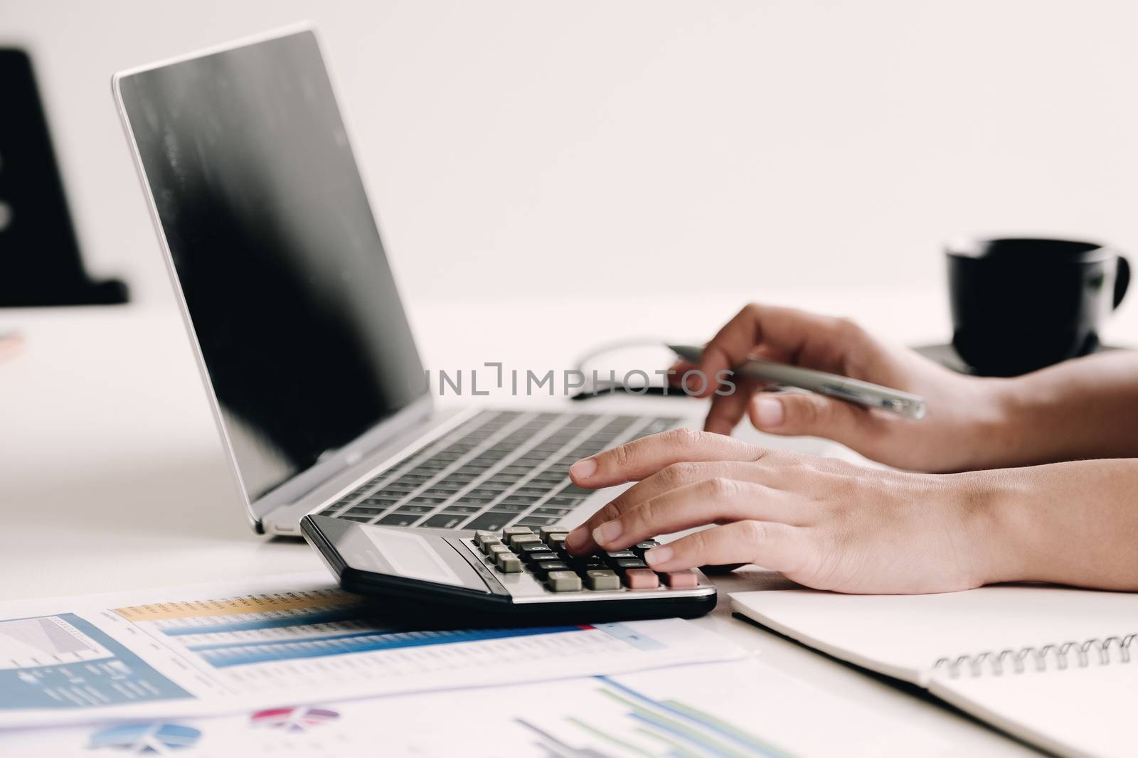 Close up Business woman using calculator and laptop for do math  by wichayada