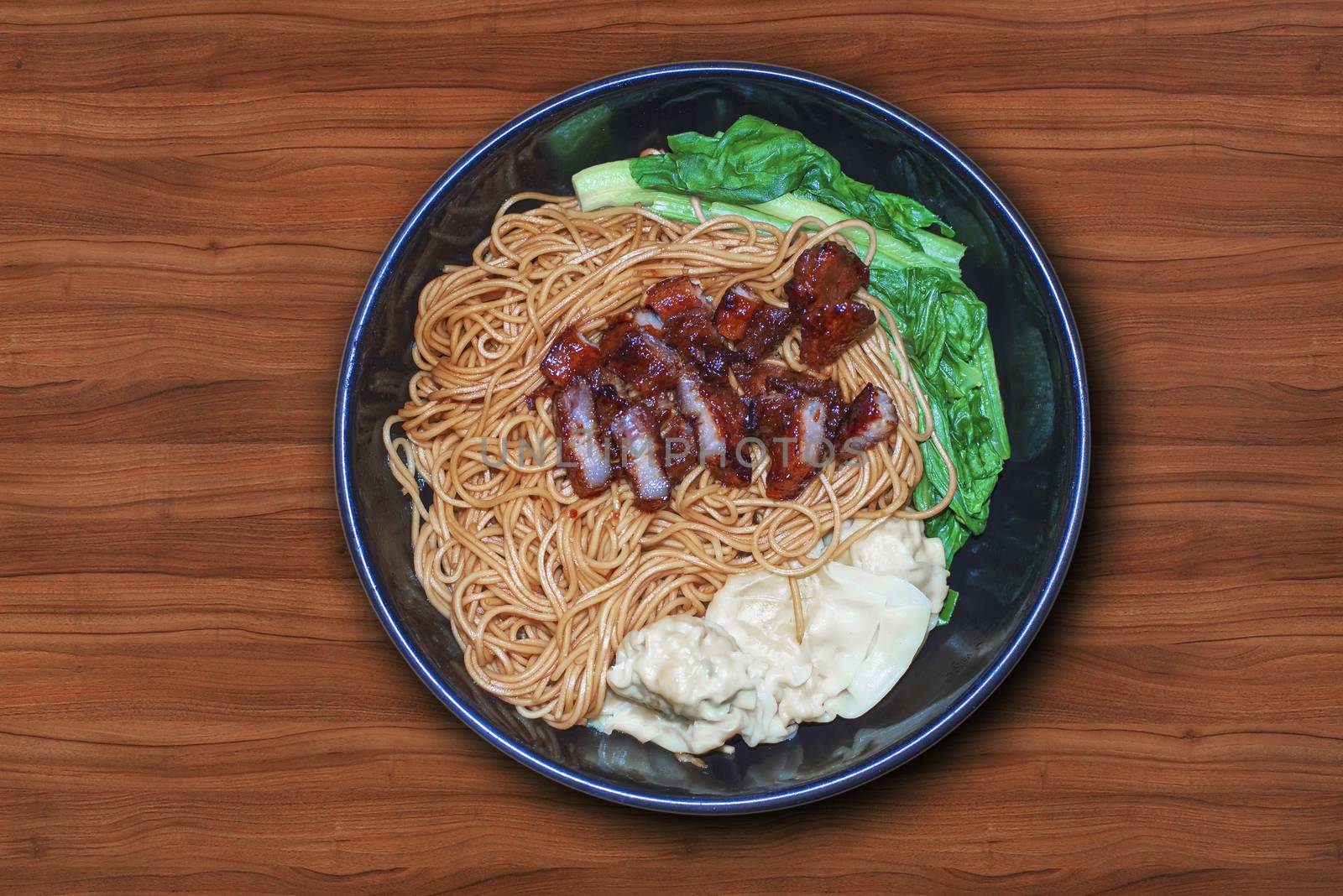 Traditional Chinese wantan mee noodle  served with char siew braised pork and cabbage on dark wooden table