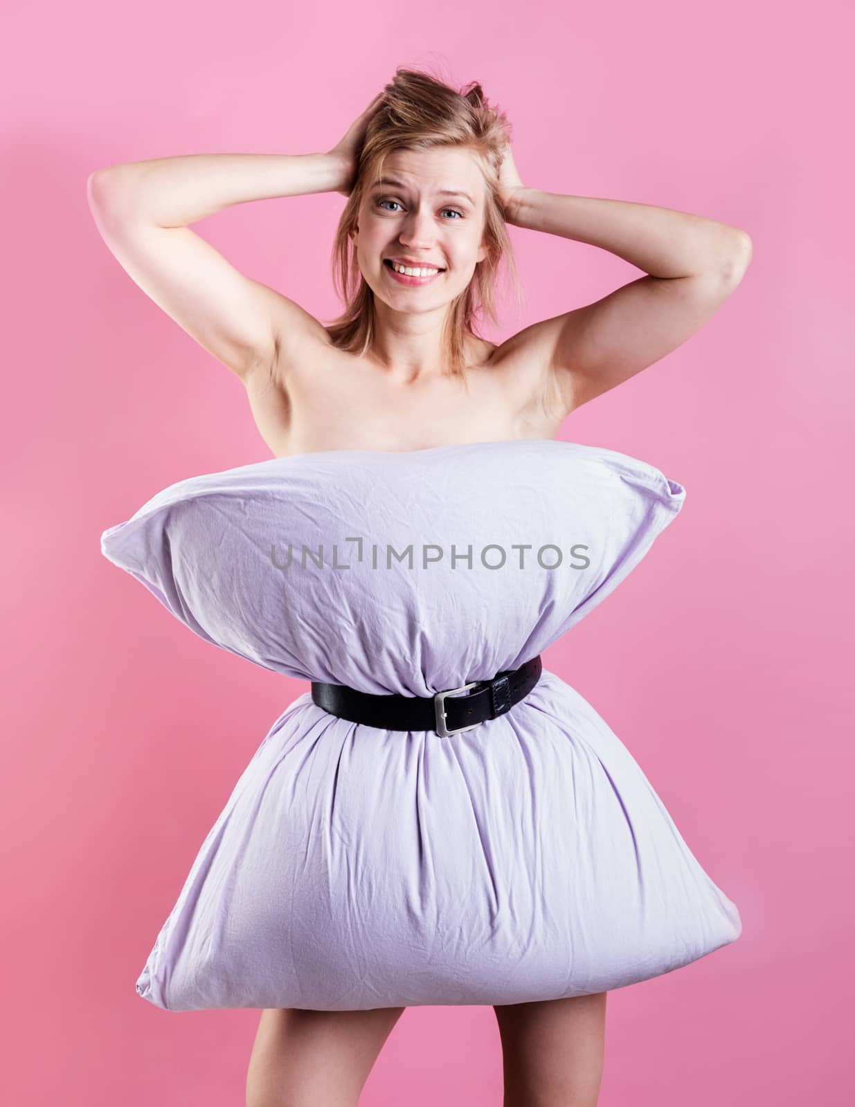 young beautiful woman dressed in pillow laughing isolated on pink background by Desperada