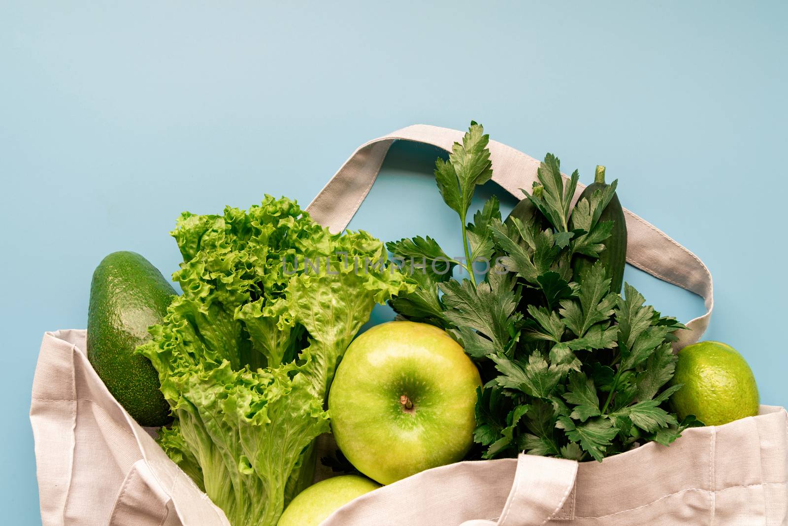 Eco bag with green vegetables top view on blue background with copy space by Desperada