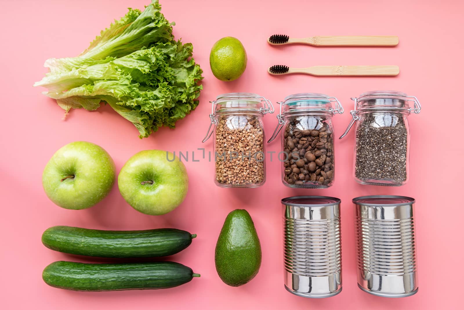 Coronavirus food supplies concept. Vegetables, canned food, wooden toothbrushes layout top view on pink background