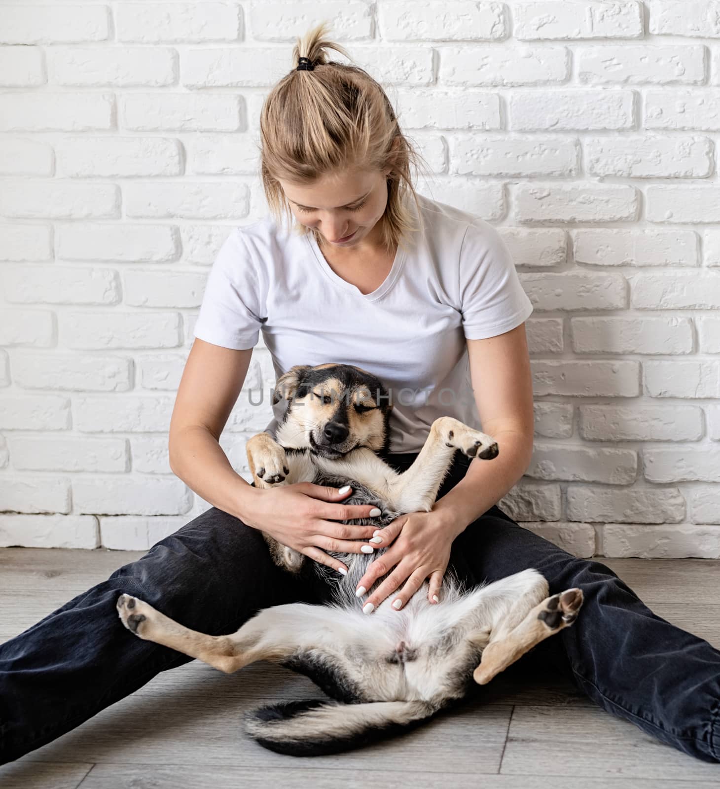 Blond woman holding her dog at home by Desperada