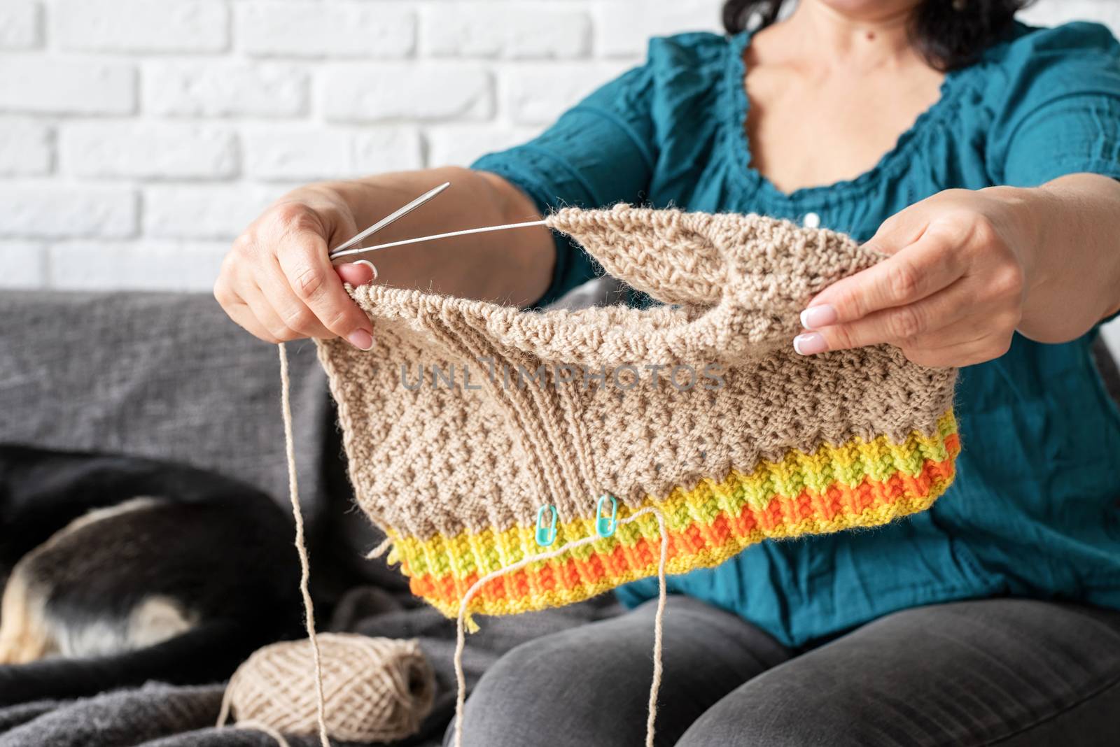 middle aged woman enjoying being at home and knitting sitting on the sofa by Desperada