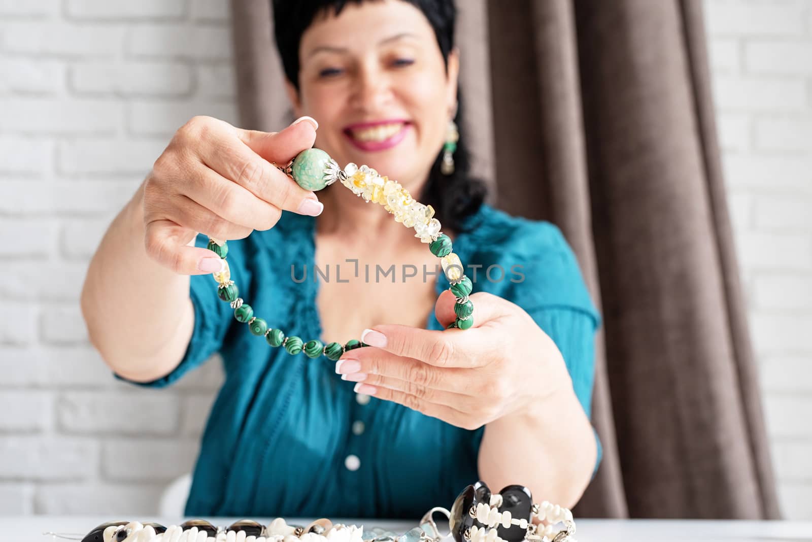 Beautiful smiling middle aged woman admiring the jewel necklace by Desperada