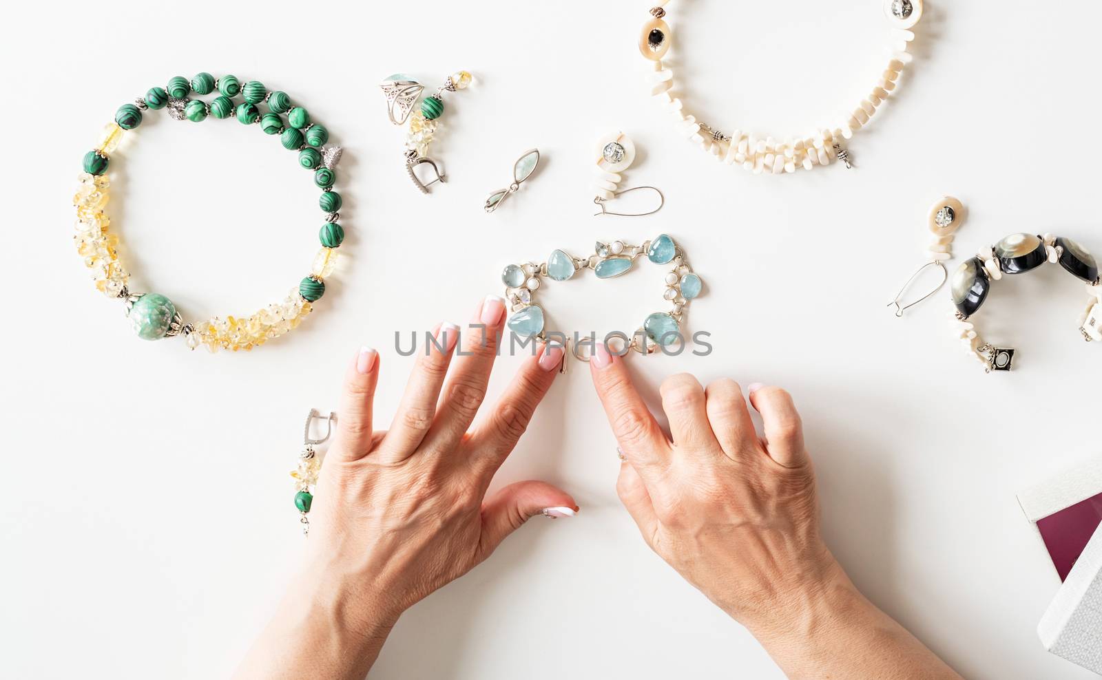 Top view middle-aged woman hands working on jewels on white table