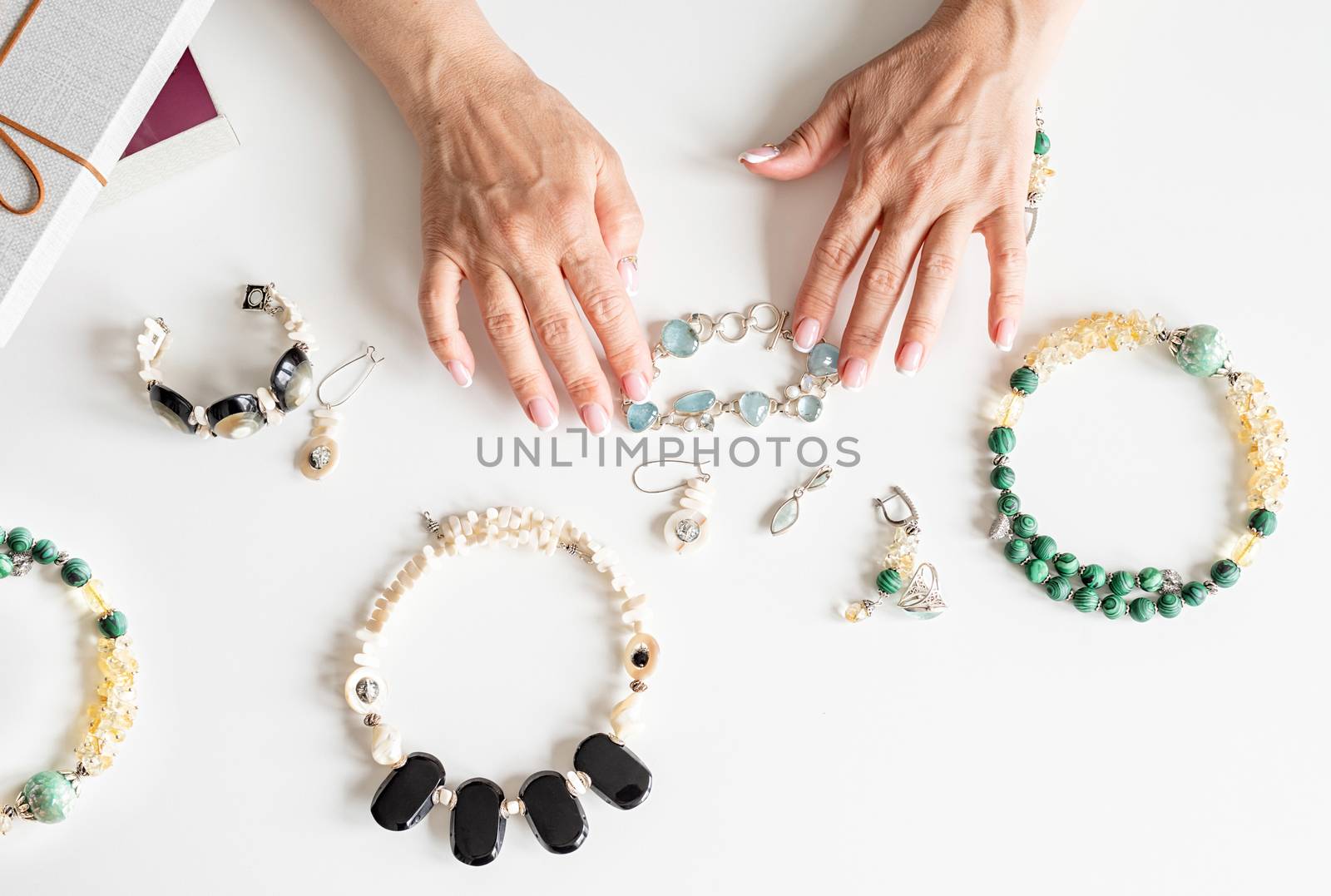 Top view middle-aged woman hands working on jewels on white table