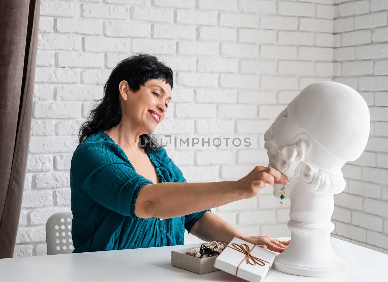 Beautiful middle aged woman trying on the jewelery on the mannequin by Desperada