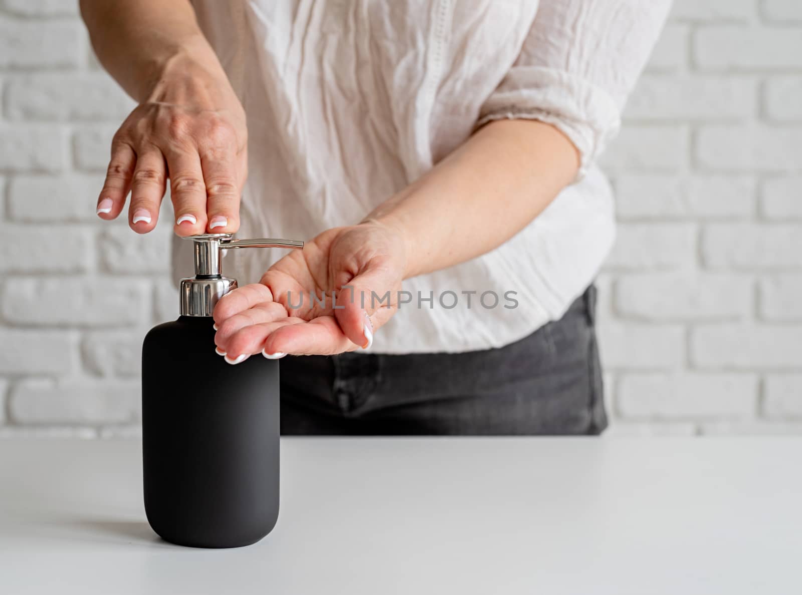 Woman hands using sanitizing gel pump dispenser by Desperada