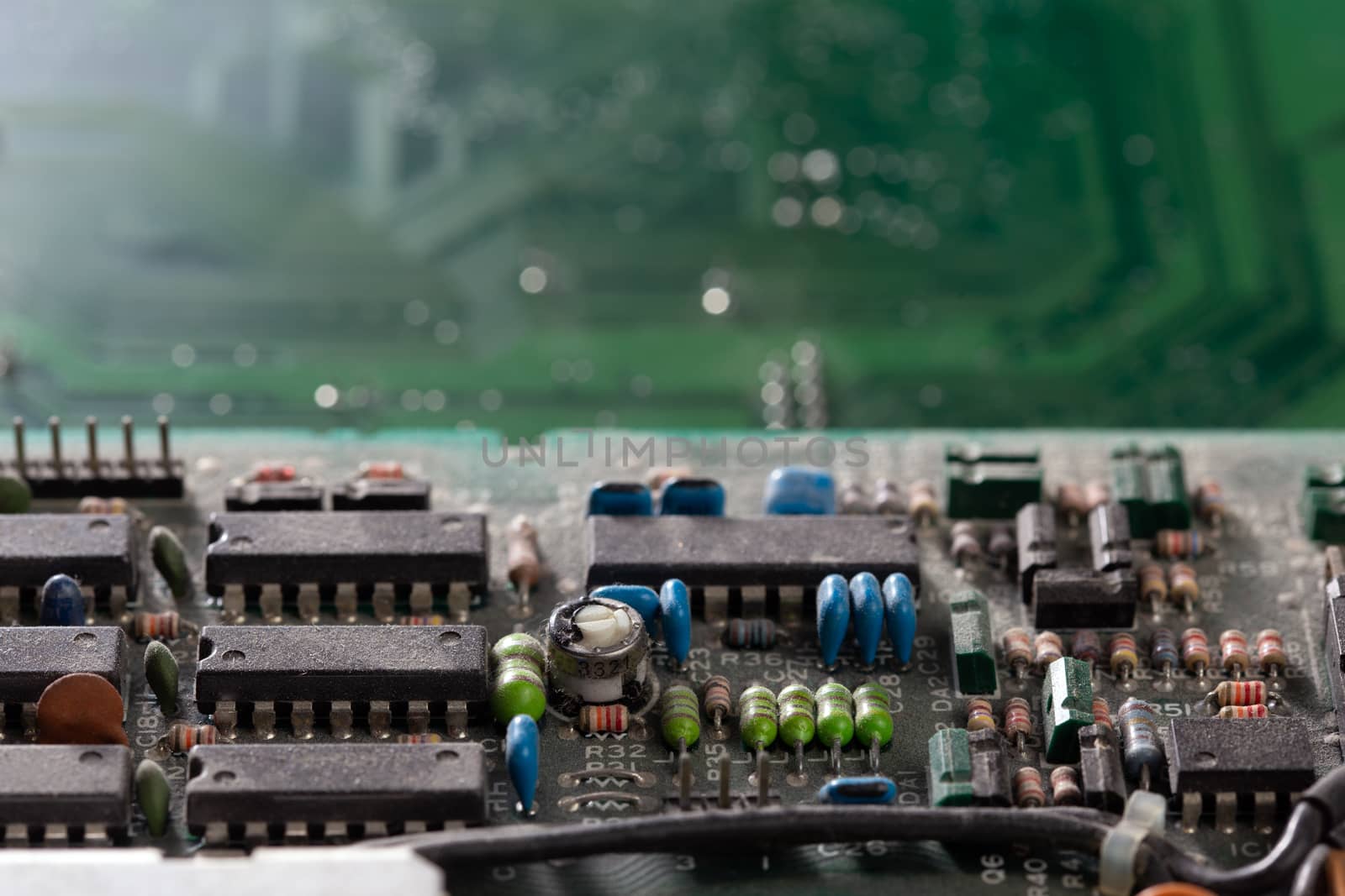 background of old electronic circuit board closeup in dark colors with dust and selective focus blur