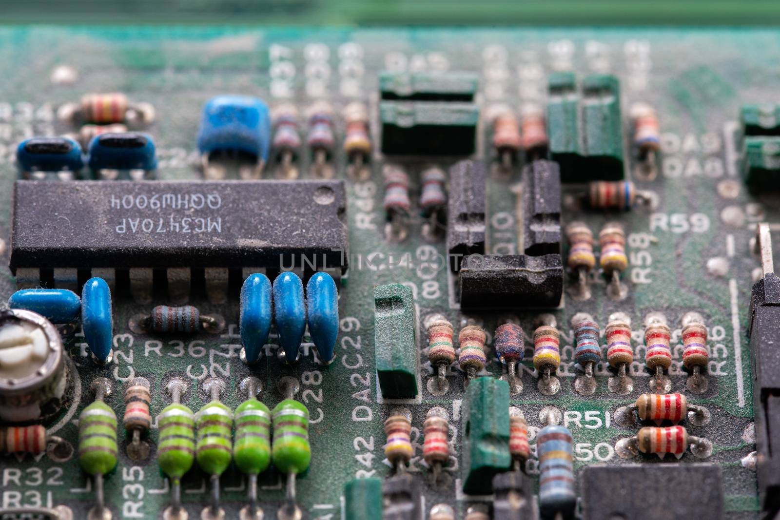 background of old electronic circuit board closeup in dark colors with dust and selective focus