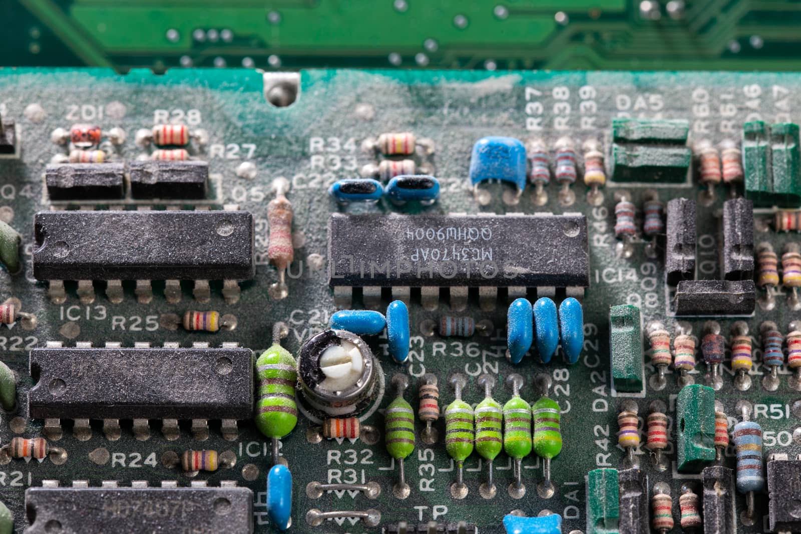 background of old electronic circuit board closeup in dark colors with dust and selective focus