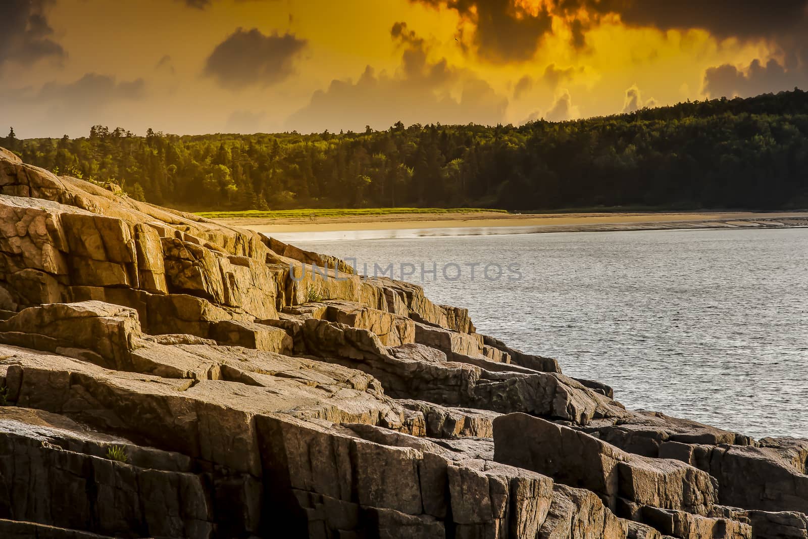Rocky coastline with golden lights and clouds on sky