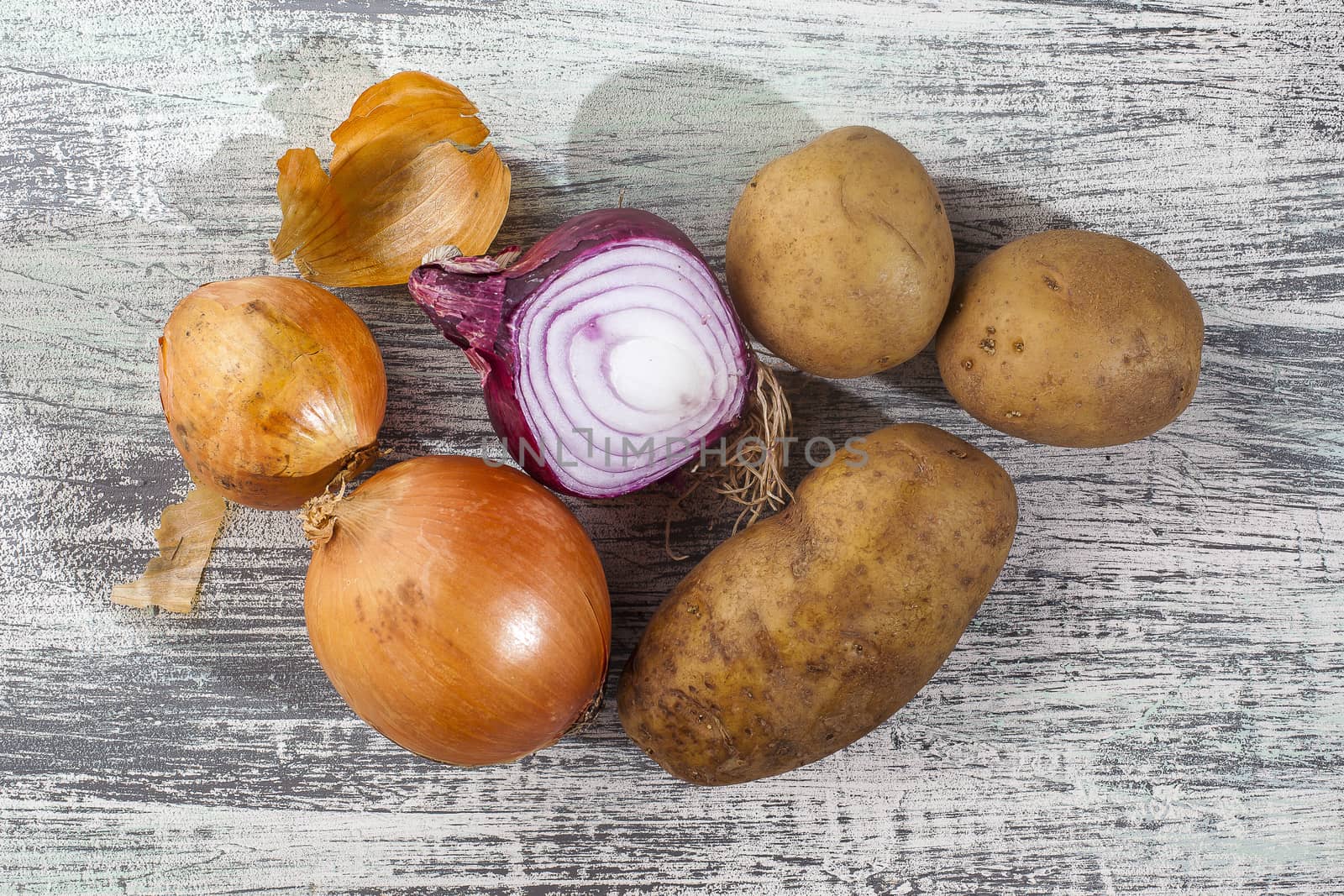 Onions with potatoes on gray and white background on sunlight