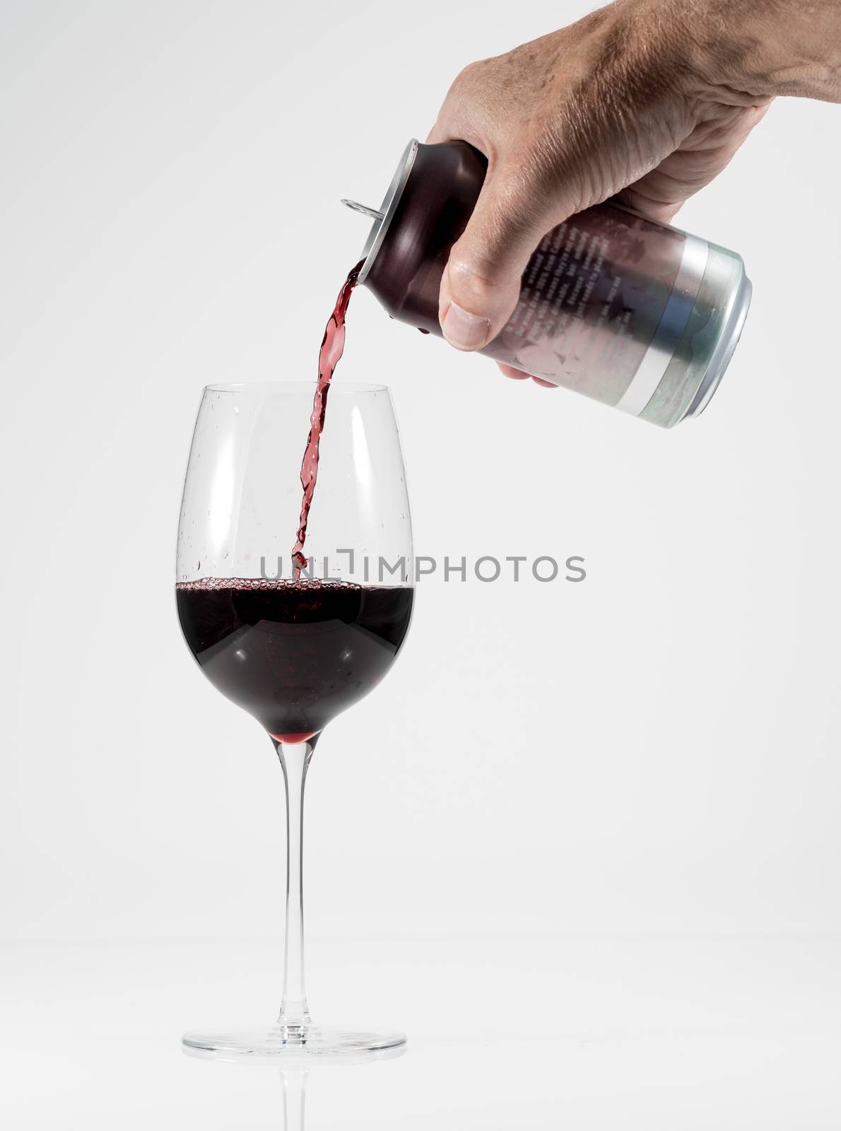 Senior man hand pouring a glass of red wine from a single serving can