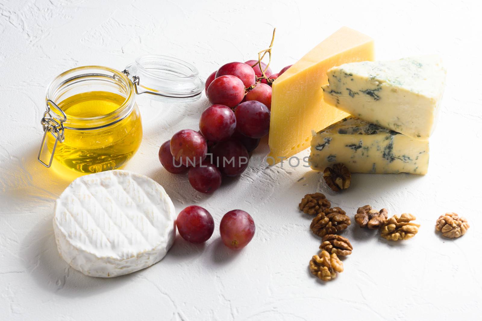 ssorted cheeses, grapes, nuts over white background, Italian and franch cheese and fruit platter with honey and wine. side view by Ilianesolenyi