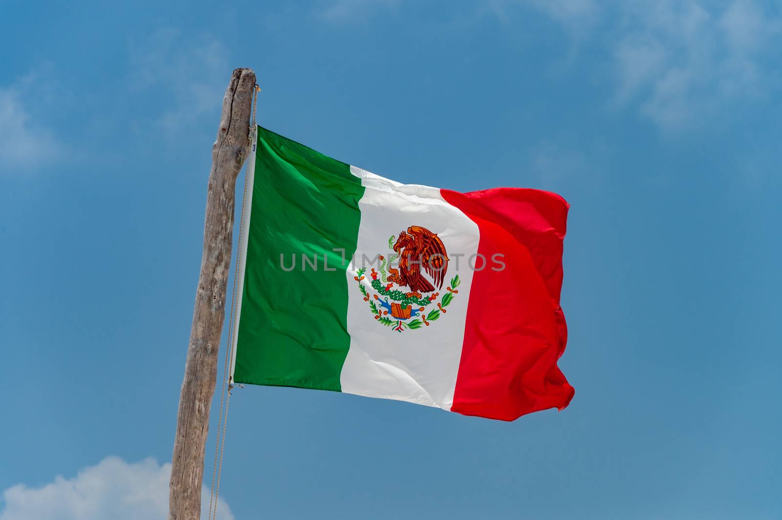 Mexican flag over blue sky in Tulum, Mexico.