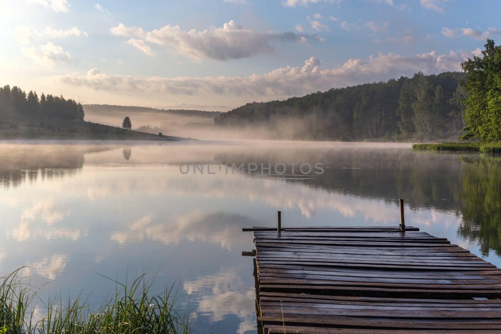 foggy summer sunrise over the river with a wooden pier