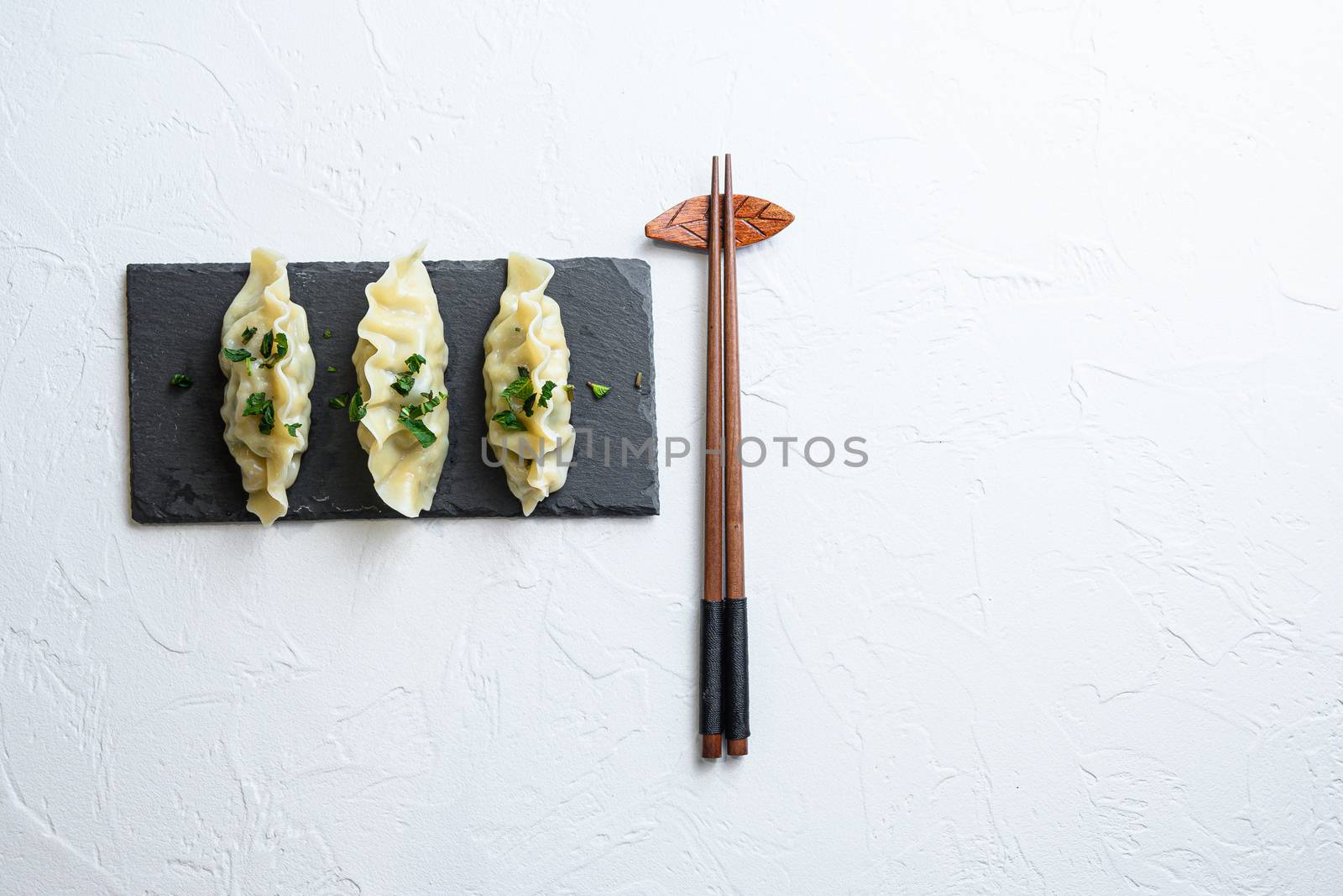 Kimchi dumplings meat dumplings on black stone plate over white textured background top view space for text nobody.