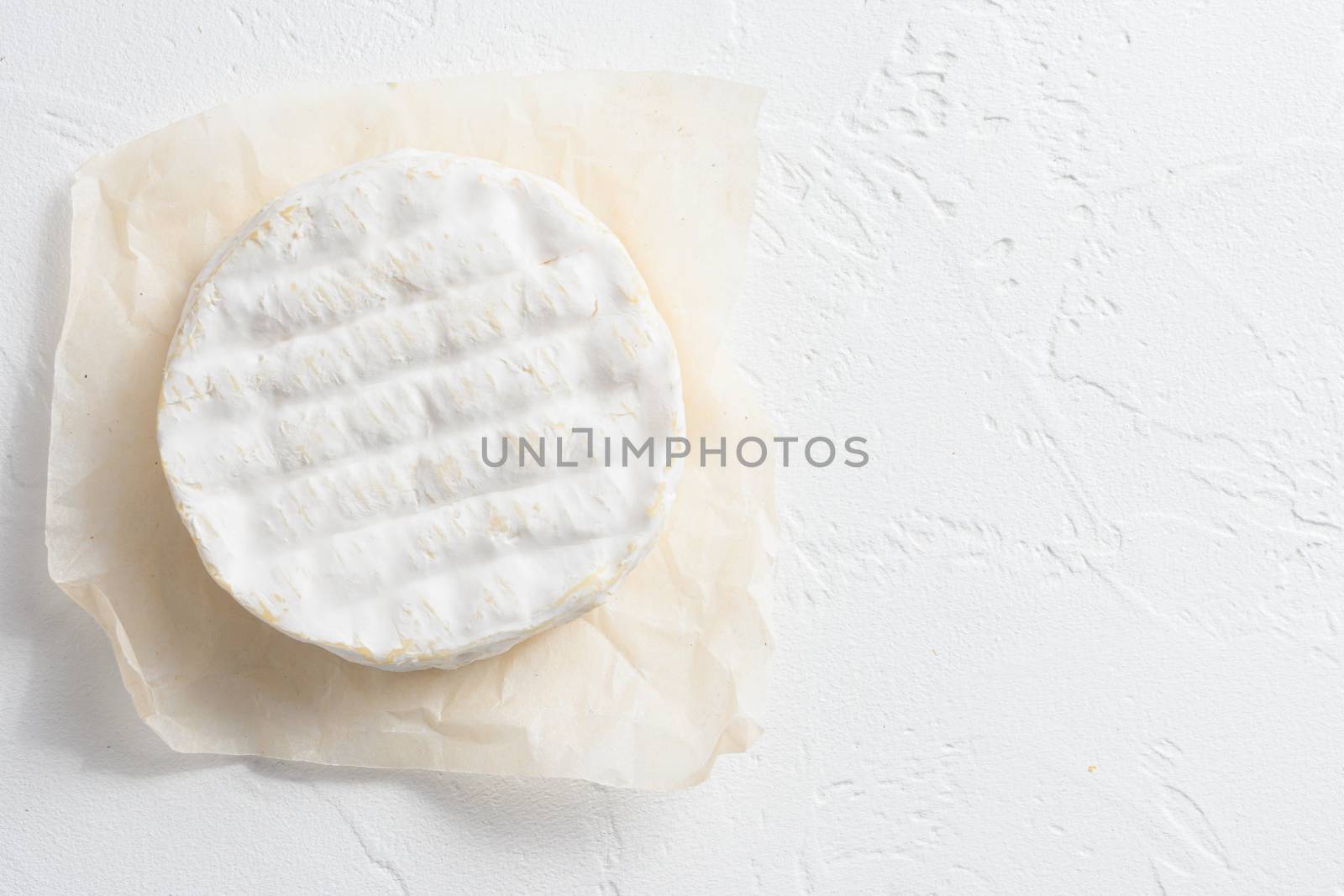 Neufchatel cheese and a Camembert cheese of Normandy on white stone surface top view space for text.