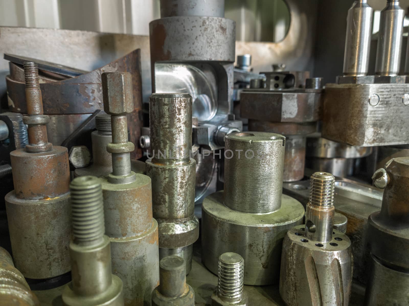A lot of old rusted machining stock holders dark industrial background with selective focus.