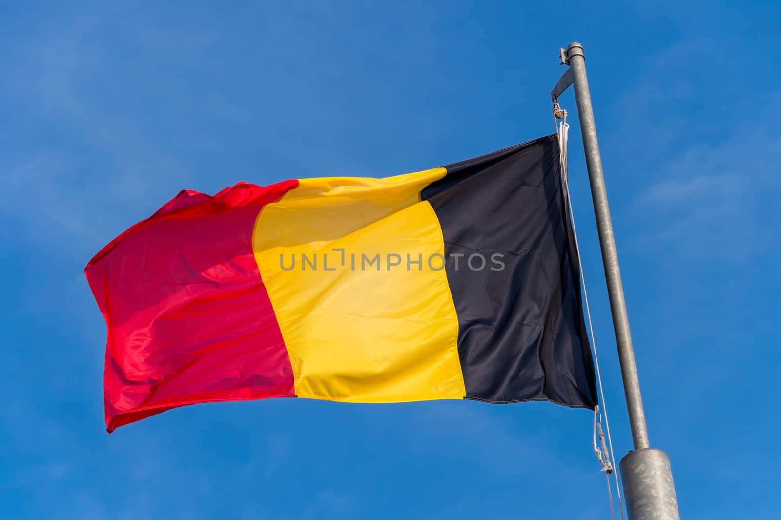 Belgian flag waving against blue sky in Boulogne sur Mer, France.