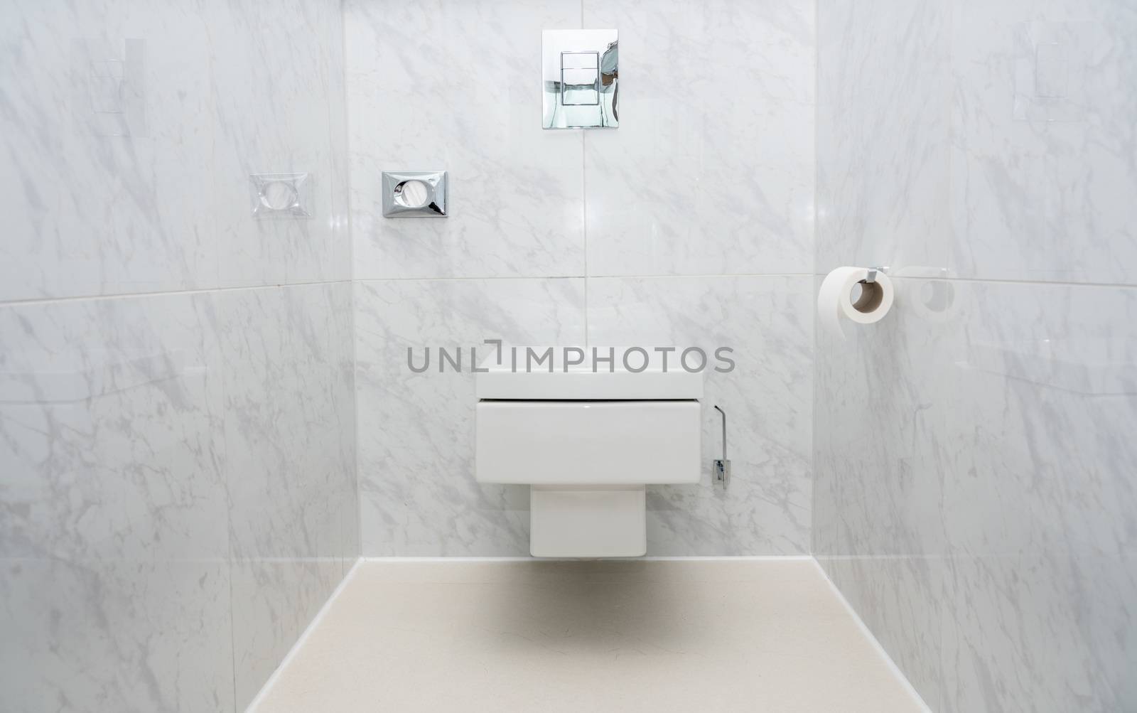 Wall mounted minimalist toilet or WC in luxury tiled bathroom with push button flush