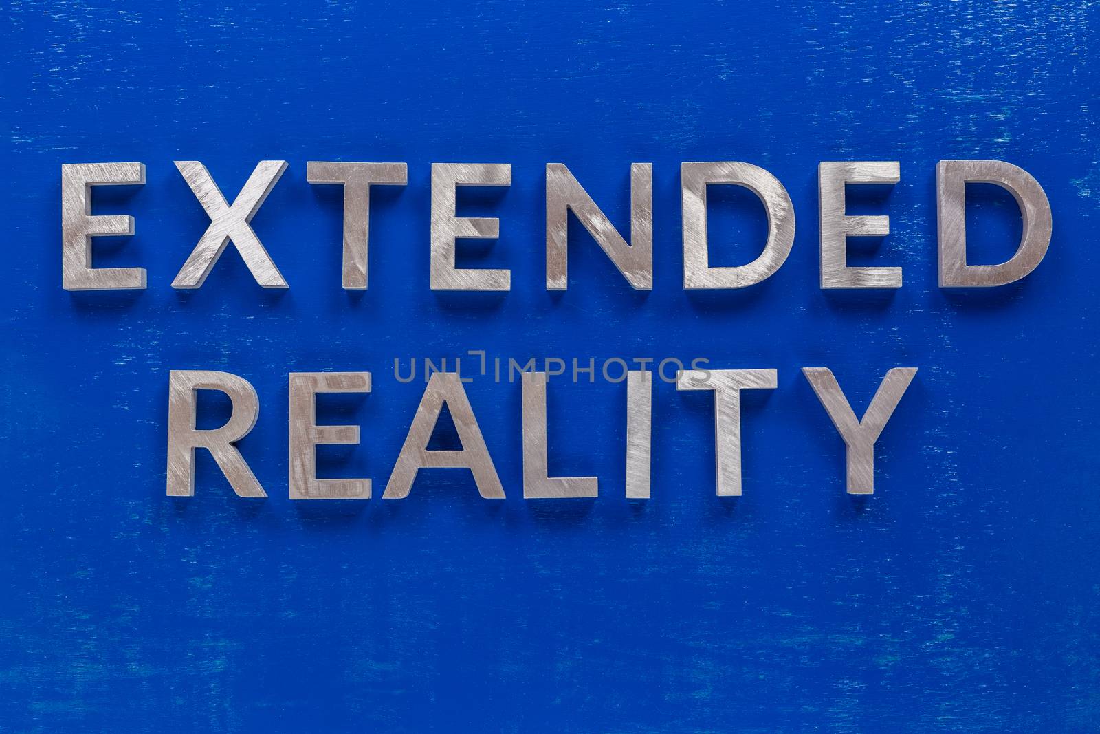 The words extended reality laid on blue painted board with thick silver metal aphabet characters. by z1b