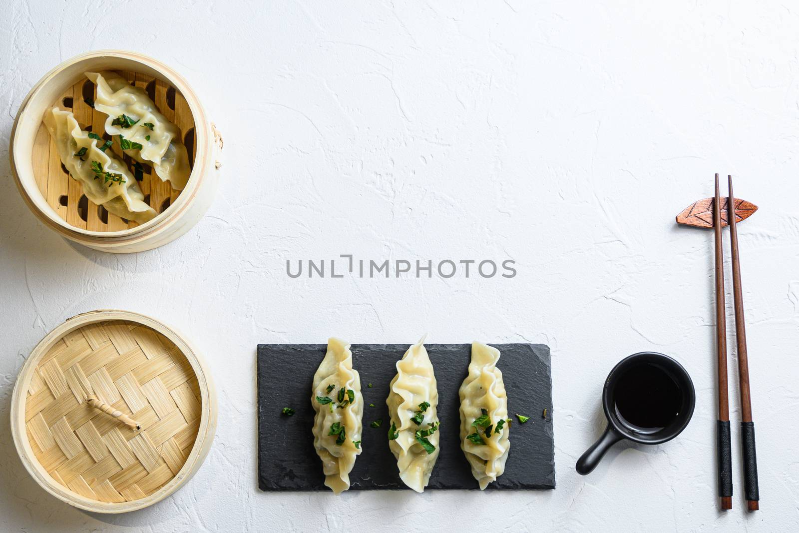 concept hinese snacks. chinese steamed dumpling Japanese gyoza or dumplings snack in wooden steamer and served on black slate with soy sauce Chinese Traditional cuisine top view space for text. by Ilianesolenyi