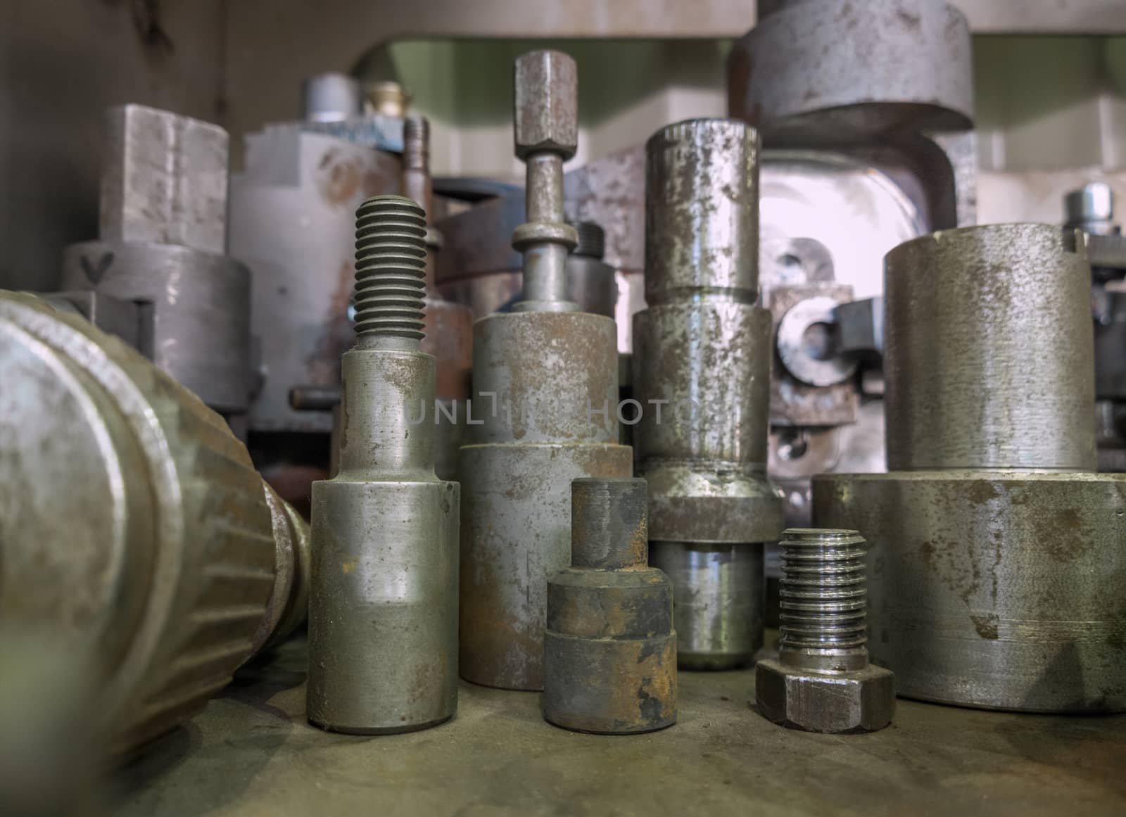 A lot of old rusted machining stock holders dark industrial background with selective focus.