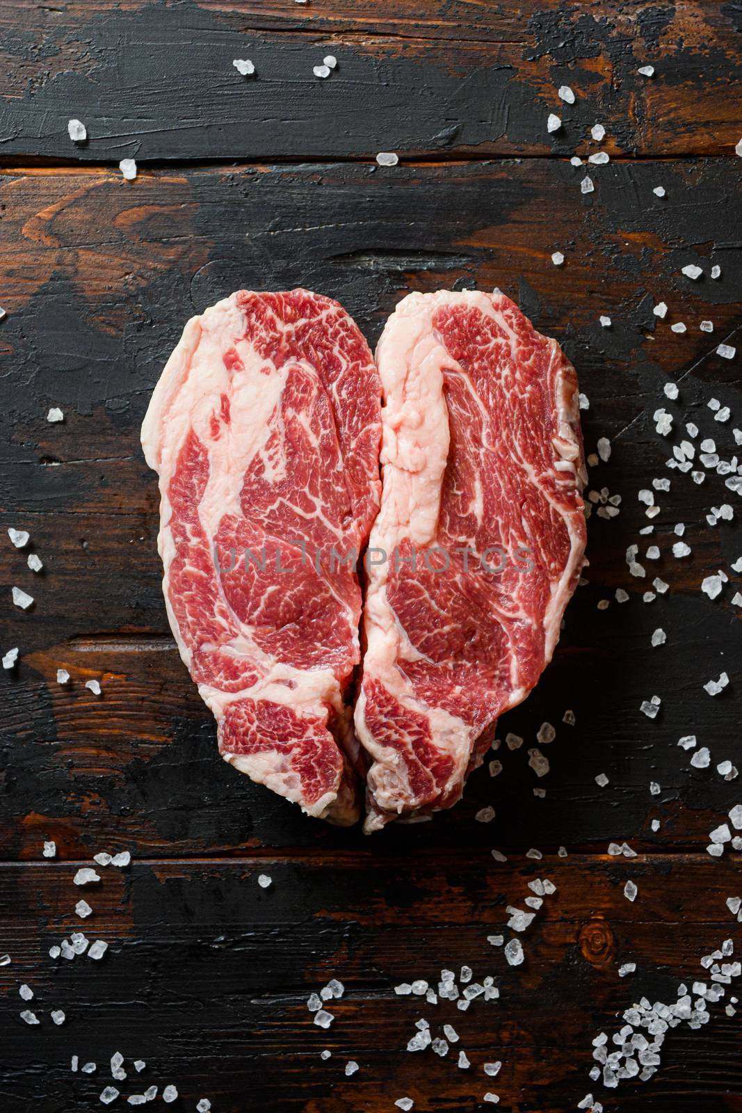 Heartshape Raw Chuck beef steak on vintage dark wood table Organic beef. Black Top view. by Ilianesolenyi