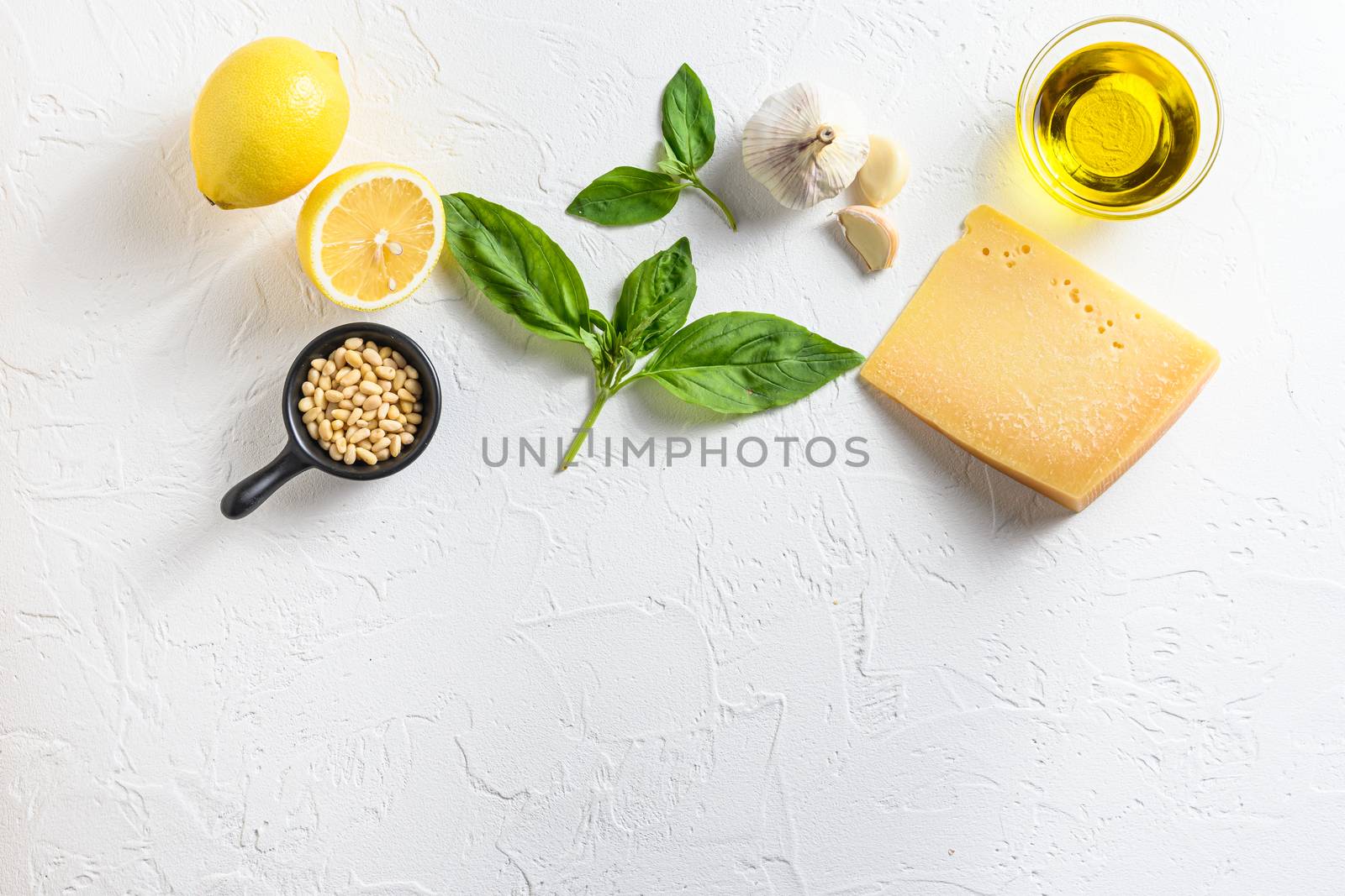 Pesto ingredients Parmesan cheese, basil leaves, pine nuts, olive oil, garlic and salt. Traditional Italian cuisine. white background with a space for a text, view from high angle.