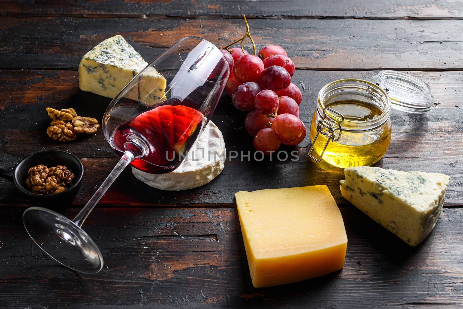 Christmas Variety of French Cheeses, camembert parmesan red Grapes, Walnuts, Honey and wine glass side view.