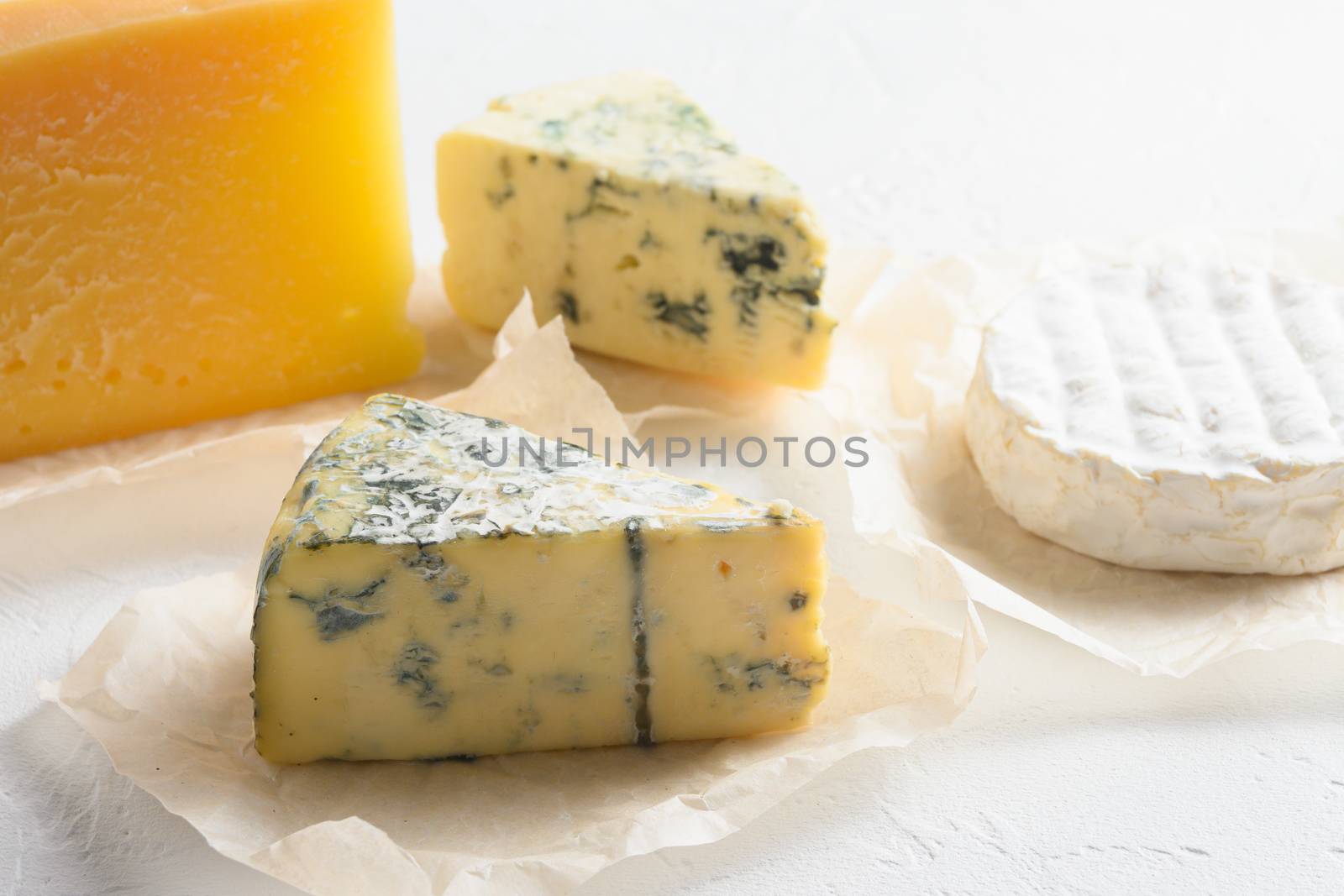 Cheese platter: yellow Maasdam, white Camembert and blue cheese Dor Blue on white background. Copy space. Concept serving cheese.
