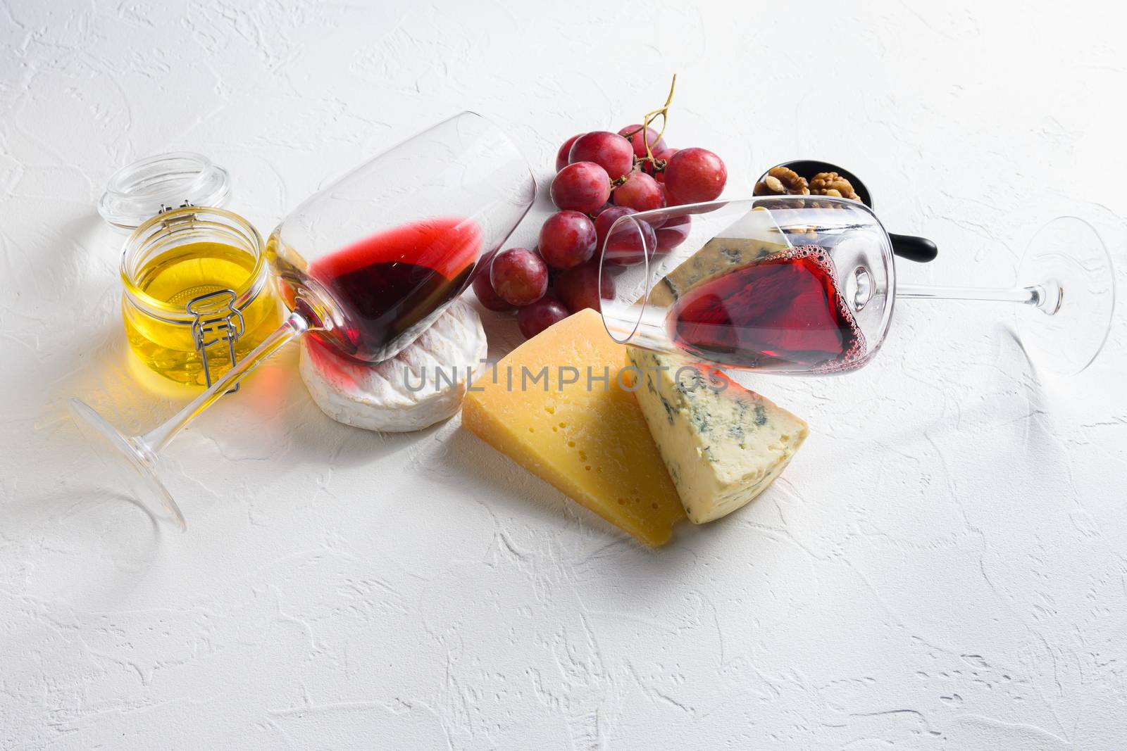 Two red wine glass with Cheese appetizer selection or whine snack set. Variety of cheese, grapes, pecan nuts side view space for text by Ilianesolenyi