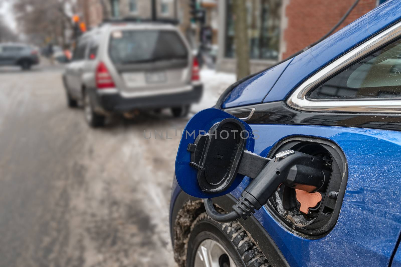 Electric car plugged in and charging in the wintertime (Montreal by mbruxelle