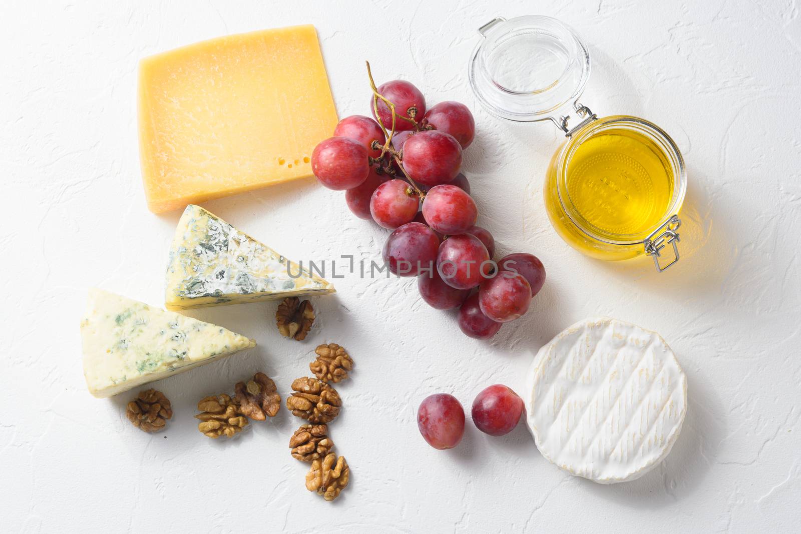 assorted mix cheeses, grapes, nuts over white background, Italian and franch cheese and fruit platter with honey and wine. top view by Ilianesolenyi