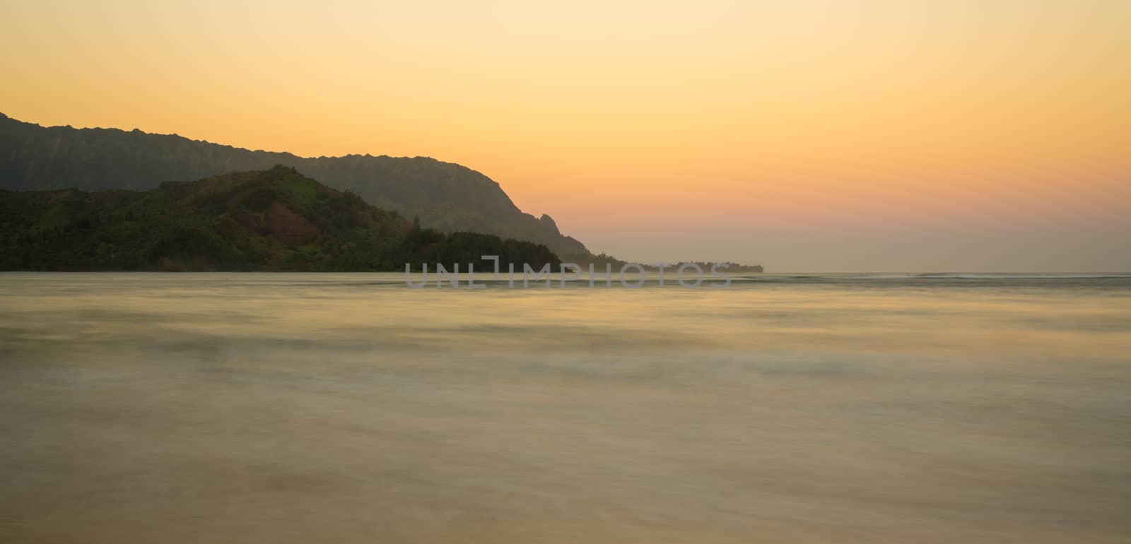 Sunrise lights the dawn sky above Hanalei Bay with the Na Pali coast in the background near Hanalei, Kauai, Hawaii