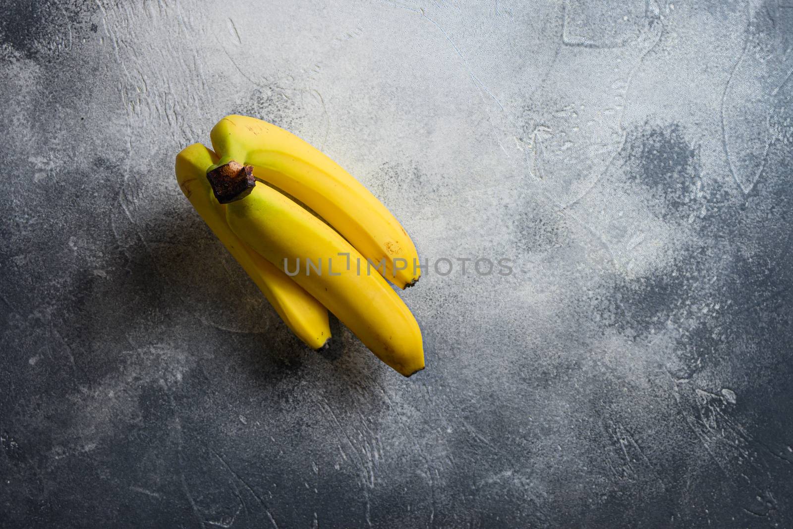 Raw Organic Bunch of Bananas Ready to Eat on kitchen stone table with copyspace.