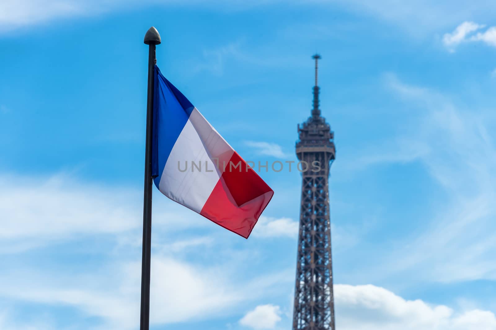 French flag waving against blue sky and Eiffel Tower by mbruxelle