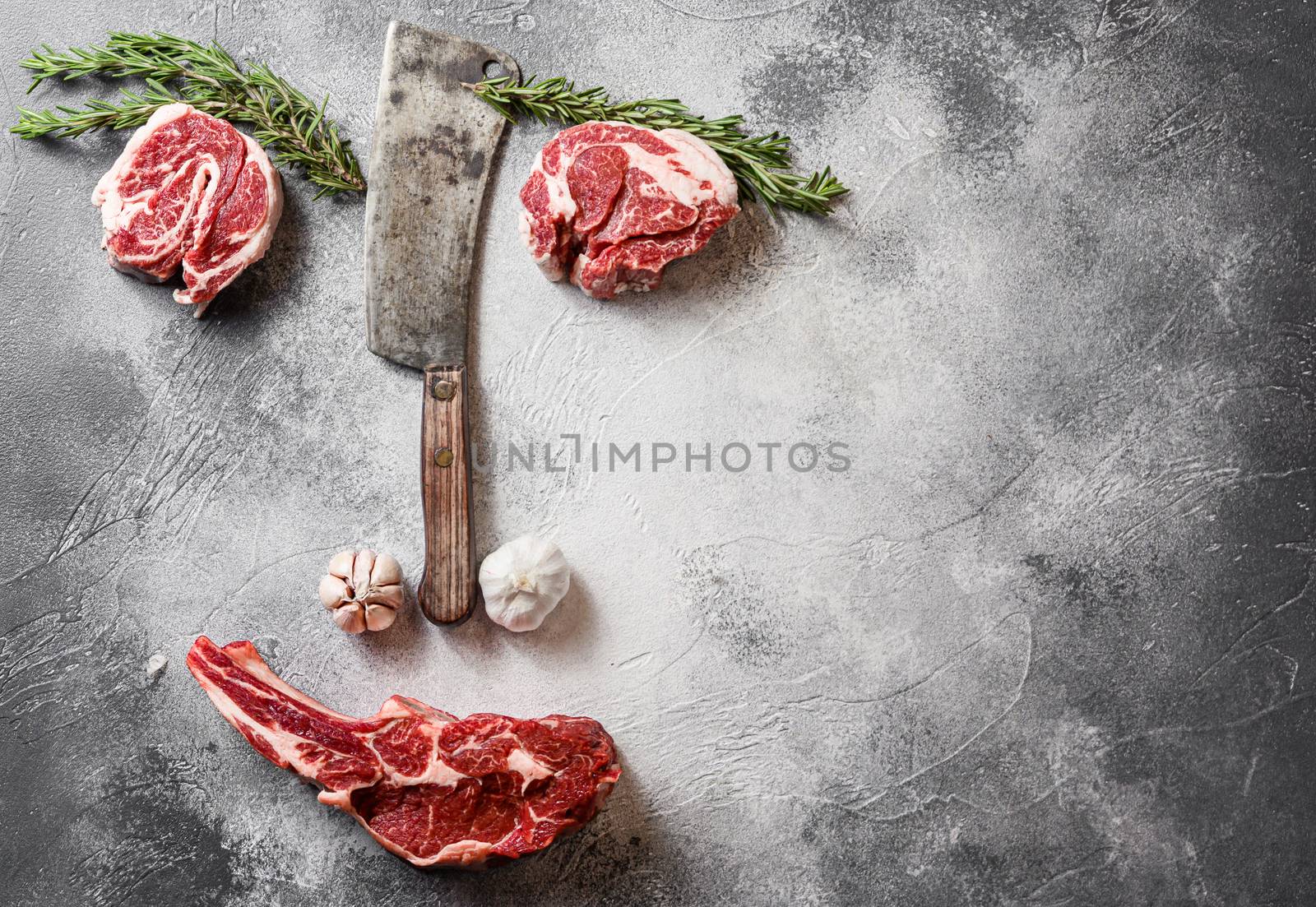 Various beef Cowboy steak happy face art style emotion with space for text. or Ribeye Steak, BoneIn, with chuck eye roll cut with the meat american cleaver knife over grey stone table slate cutting top view sad face styled art with seasonings, tomatoes, garlic, rosemary/
