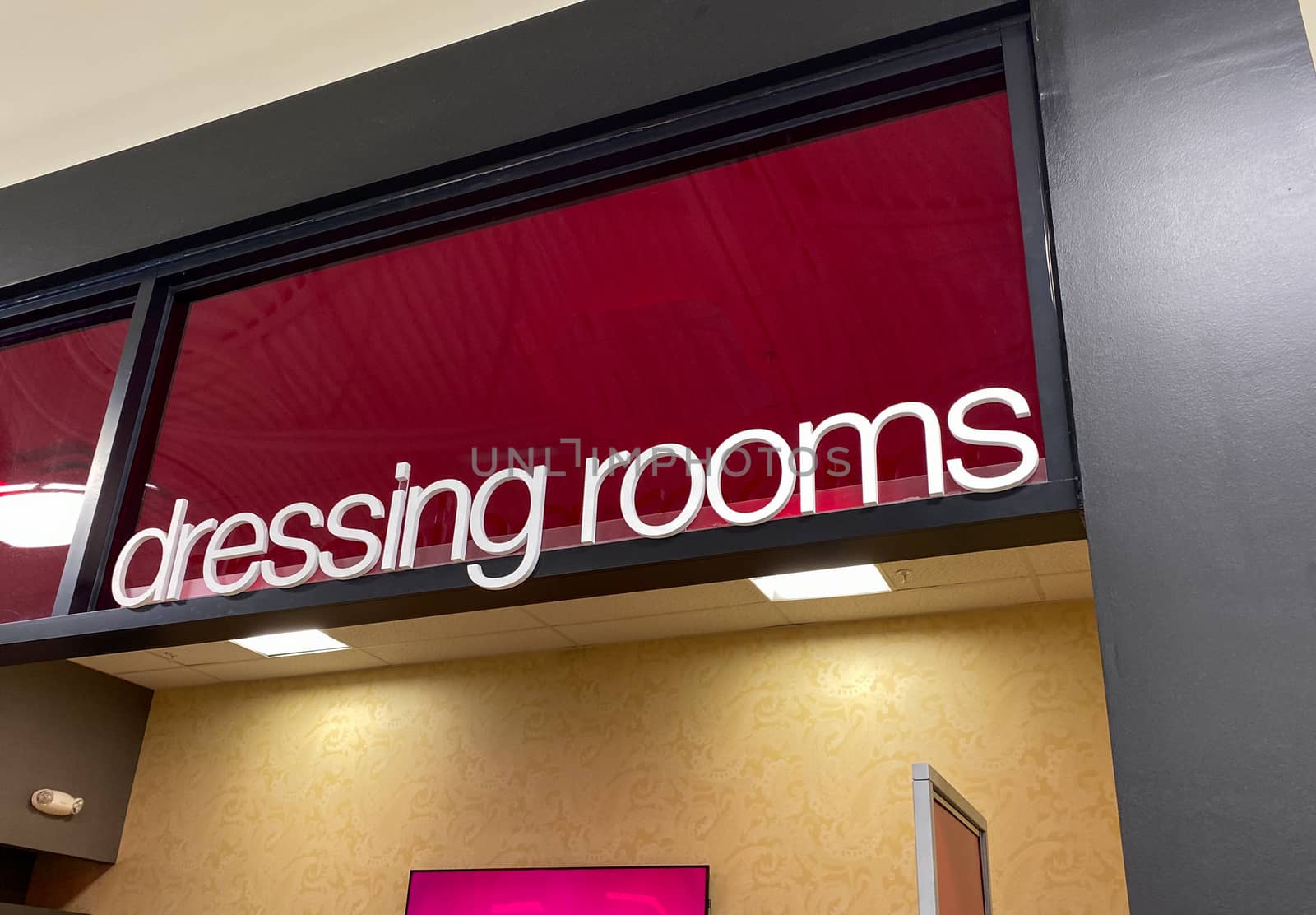 The dressing room sign with white letters on a red background at a retail clothing store.