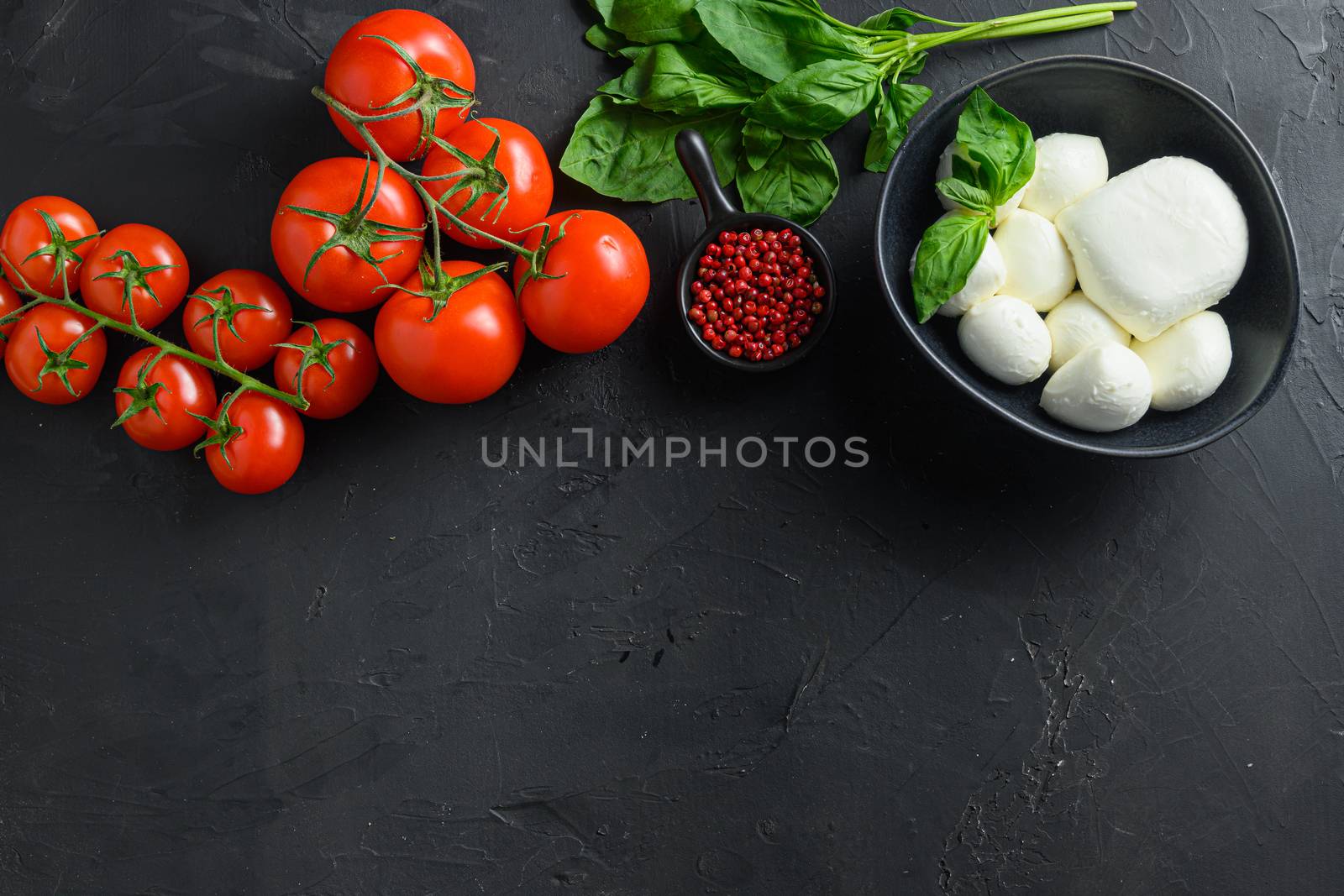 Mozzarella cheese balls, cherry tomatoes and green fresh organic basil italian cuisine . Ingredients for caprese Organic Mediterranean food concept, flat lay top view space for text black table by Ilianesolenyi